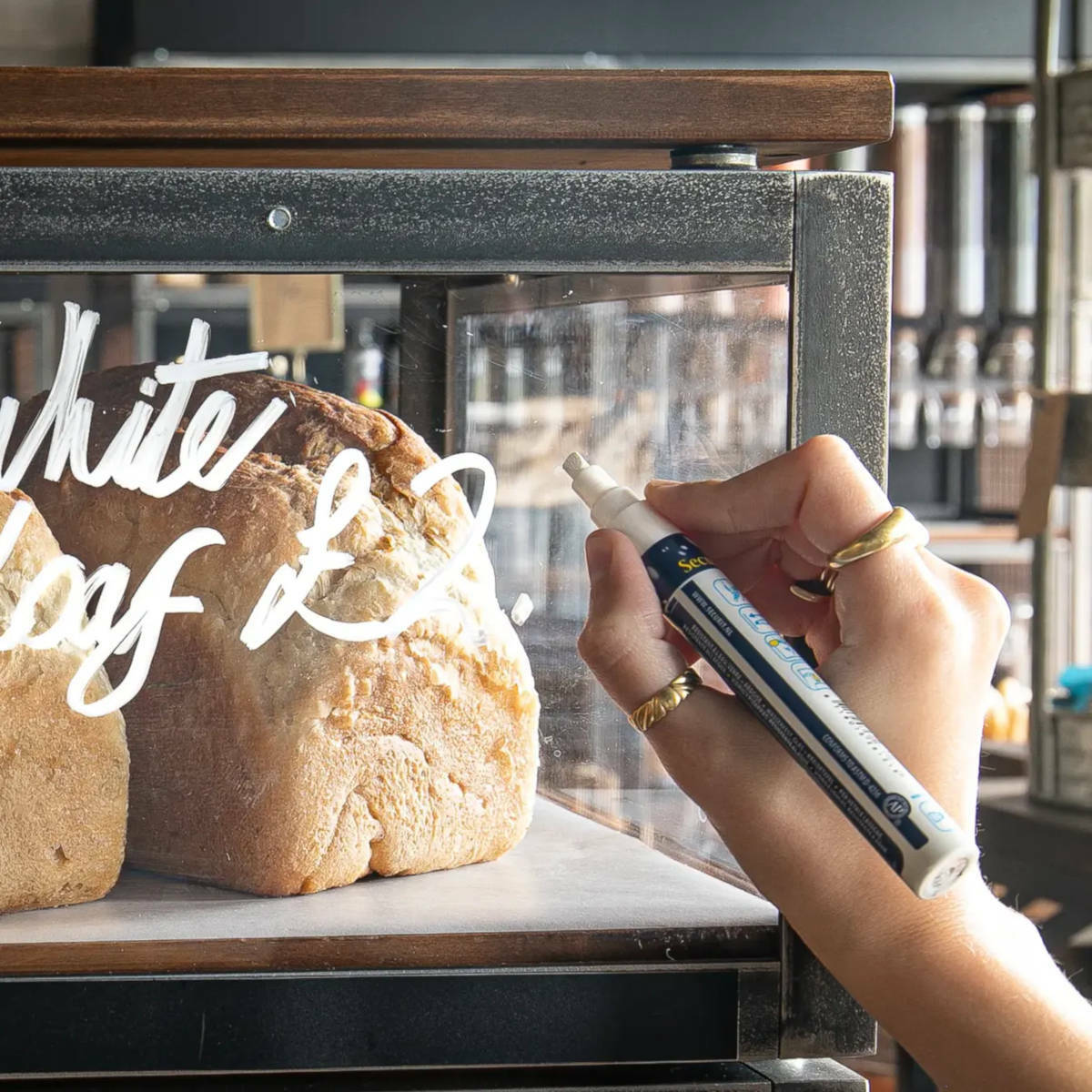 Hand holding a chalk pen against some glass