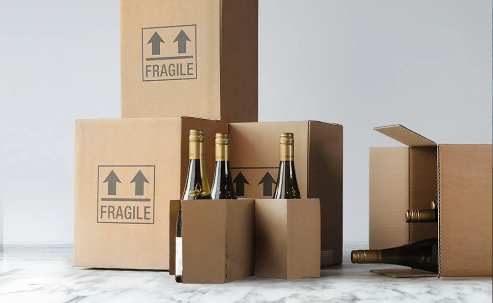 Boxes with fragile written on them, some on their side with wine bottles sticking out