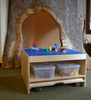 Playscapes 3-Branch Discovery Mini Children's Activity Table, showing a wooden table with a blue Lego baseplate on top, surrounded by a tree-shaped structure in the background.