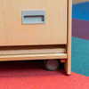 Playscapes 3-Branch Discovery Mini Activity Table, wooden furniture with a small drawer and a wheel at the bottom on colorful carpet.