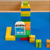 Playscapes 3-Branch Discovery Mini Activity Table, colorful building blocks and miniature house on a blue surface.