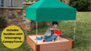 Frame It All Square Sandbox with Telescoping Canopy and Cover, 11H, showing a young boy playing with sand inside a wooden sandbox with a green telescoping canopy and cover outdoor setting.