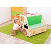 Moje Bambino Sensory Truck, a wooden children's play bed designed as a colorful truck with a green backrest, orange and yellow accents, and a fun face illustration, placed on a green rug in a child's room.
