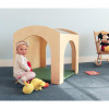 Whitney Brothers Nature View Reading Retreat Set, wooden playhouse for children with a baby girl sitting inside along with plush toys, in a playroom with a Mickey Mouse plush on a rocking chair and a children's book on the floor.