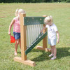 Infinity Playgrounds Chime Wall Activity Center, Children playing with the musical chime wall outdoors on green grass.