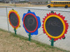 Infinity Playgrounds Chalkboard Flowers - Daisy, Rose or Sunflower, colorful flower-shaped chalkboards with black writing surfaces, placed on a wire fence outdoors.