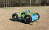 Infinity Playgrounds Jeep Playground Spring Rider, green and blue jeep-shaped outdoor playground equipment with rubber tires and spring base on a grassy field.