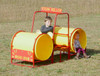 Infinity Playgrounds Steam Roller Double Tunnel Playground Climber, kids playing inside yellow tunnel structures shaped like a steam roller with red frames, outdoor grassy field.