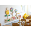 Moje Bambino Meadow Sensory Wall Panel, colorful wooden sensory wall with flower and ladybug designs in a children's playroom.