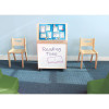 Whitney Brothers Big Book Display With Write & Wipe Back, wooden learning station with bulletin board and whiteboard for reading activities, positioned between two wooden chairs in a classroom setting.