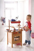 HABA Pro Mini Wooden Play Kitchen Block, child playing with a miniature wooden kitchen set in a bright, airy room.