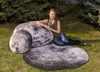 Playscapes Woodsmen Naturescapes Moon Pod, outdoor moon-shaped cushions and seating resembling the moon's surface, placed on green grass with a girl sitting beside them in a natural setting.