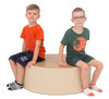Moje Bambino Nature Inspired Xtra Large Pouf, beige round seating cushion with two young boys sitting on it, one wearing an orange t-shirt and navy shorts, the other wearing a green t-shirt and shorts, on a plain white background.