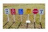 Infinity Playgrounds Playground Traffic Signs For Trike Tracks, collection of colorful toy traffic signs with various messages including one way, no parking, accessible, yield, stop, and speed limit, arranged in a row on a grassy area.