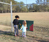 Infinity Playgrounds Connect 4 Playground Game, children playing a giant Connect 4 game outdoors behind a chain-link fence.