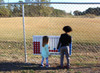 Infinity Playgrounds Connect 4 Playground Game, children playing Connect 4 game outdoors near a chain-link fence.
