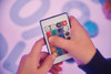 TickiT Sensory Mood Light Table, close-up of a person's hand holding a remote control to operate the sensory mood light table with colorful lighting in the background.