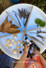TickiT Sensory Mood Discovery Light Table, featuring natural objects such as leaves, sticks, pinecones, seashells, and a remote control for lighting effects arranged on a round, light-up display table.