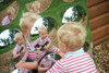 SPARK & WOW Acrylic Bubble Mirror - 9 Giant Bubbles, a colorful acrylic mirror with multiple small and one large reflective bubbles, reflecting a young boy in a red and white striped shirt outdoors in a park setting. SPARK & WOW Acrylic Bubble Mirror - 9 Giant Bubbles, a colorful acrylic mirror with multiple small and one large reflective bubbles, reflecting a young boy in a red and white striped shirt outdoors in a park setting.