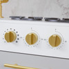 Teamson Kids Versailles Play Kitchen with Refrigerator and Cookware Accessories, close-up of a white toy stove featuring three gold dials for temperature control and function settings.