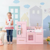 Teamson Kids Little Chef Charlotte Modern Pink Play Kitchen, a children's play kitchen set in pink with realistic stove, oven, sink, and refrigerator, in a colorful playroom.
