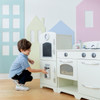 Teamson Kids Little Chef Fairfield Ivory Retro Play Kitchen, a child playing with a white play kitchen set in a colorful room.
