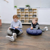 Children's Factory Mini Round Pouf with Handle - Gray and Navy, children sitting on the floor with the pouf in a playroom setting.