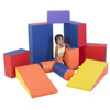 Children's Factory Soft Shapes Foam Climbing Blocks Set, Rainbow, colorful foam blocks arranged in a playful structure with a smiling child standing among them.