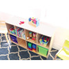 Whitney Brothers 8 Cubby Backpack Storage Cabinet, wooden cubby organizer with multiple compartments filled with children's books, toys, and art supplies in a classroom setting.