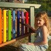 Playmore Designs 8 Note Rainbow Chime Unit, colorful outdoor musical instrument with rainbow-colored tubes in a playground setting.