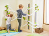 HABA Pro Wooden Balls for Velcro Ball Run, 6-Piece Set, children playing with the ball run system with white tracks and green connectors mounted on a wall in a playroom.
