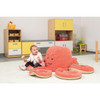 Moje Bambino Otto the Octopus Friendly Soft Seat For 6, plush octopus-shaped kids' seating with smiling face, soft pink color, and multiple tentacle seating areas, in a child-friendly playroom setting.
