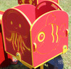 Infinity Playgrounds Carrington's Carousel Toddler Easy Rider Merry Go Round, colorful red and yellow kiddie ride with ocean-themed jellyfish and fish cutouts design.