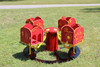 Infinity Playgrounds Carrington's Carousel Toddler Easy Rider Merry Go Round, colorful red and yellow toddler merry go round with bug, starfish, and sea creature designs on the side panels in a park setting.