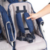 Angeles SureStop BYE-BYE Folding Commercial Stroller 6 Passenger, image shows a close-up of a blue and gray stroller with a person's hand adjusting the safety harness.
