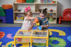 Children's Factory Mini Double Discovery Sensory Table, two young girls playing with water and toy cups in a colorful indoor play area.