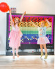LiteZilla Giant Lite Brite 6' x 5' Light Wall, large colorful light-up display with two children playing and jumping in front of it.