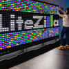 LiteZilla Giant Lite Brite 8' x 5' Light Wall, colorful illuminated light wall with a person decorating it.