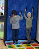 LiteZilla Clone Box Giant Pin Wall STEM Activity, two children engaging with a large interactive blue pin wall.
