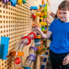 LiteZilla Kidworx Twist and Turn Tubes Wall Ball Run Bundle, young boy playing with a colorful indoor maze and ball run wall setup. LiteZilla Kidworx Twist and Turn Tubes Wall Ball Run Bundle, young boy playing with a colorful indoor maze and ball run wall setup.
