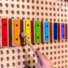 LiteZilla Kidworx Melody Magic Xylophone Wall Marble Run, colorful wooden marble run with metal chime bars on a pegboard background.