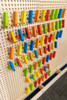 LiteZilla KidWorx™ Instant Reset Domino Dash Wall Activity, colorful wooden domino pieces arranged on a pegboard wall for children's educational and recreational activity.