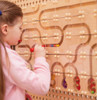 LiteZilla Kidworx Magnet Maze Marble Run Builder, young girl assembling a magnetic marble maze on a wooden board with various tracks and colorful marbles.