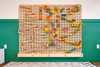 LiteZilla Kidworx™ Grid Glider Tile Challenge Wall Game, colorful wooden tiles and gear pieces on a pegboard wall for children's educational play and puzzles.