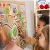 HABA Pro Children's Emergency Vehicles Wall Activity, children engaging with a wooden interactive educational wall activity featuring emergency vehicle scenes and transport elements.