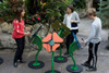 Freenotes Flower Musical Outdoor Bells, colorful flower-shaped outdoor musical instruments being played by three people in a garden setting.