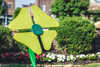Freenotes Flower Musical Outdoor Bells, colorful outdoor garden wind chime with flower-shaped design in bright green, set in a landscaped garden environment.