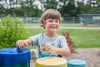 Freenotes Tuned Outdoor Congo Drums, colorful outdoor percussion instruments with a smiling child playing them in a park setting.