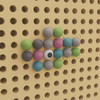 Flash Furniture Bright Beginnings Pastel Peg Accessory Pack for Modular STEAM Wall Systems - 512 Pack, colorful pastel balls and a white ball with black dot arranged on a perforated board.