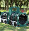 World Klass Play Train Carriage Playground Crawl Tunnel, a colorful outdoor playground train structure designed for children to crawl through and play. The train features a bright green body with black tunnel sections and is set on a grassy area with trees in the background.